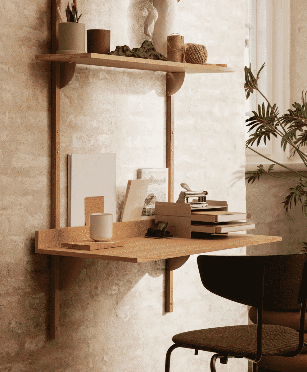 A minimalist wooden wall-mounted desk with integrated shelving in a small workspace setup.