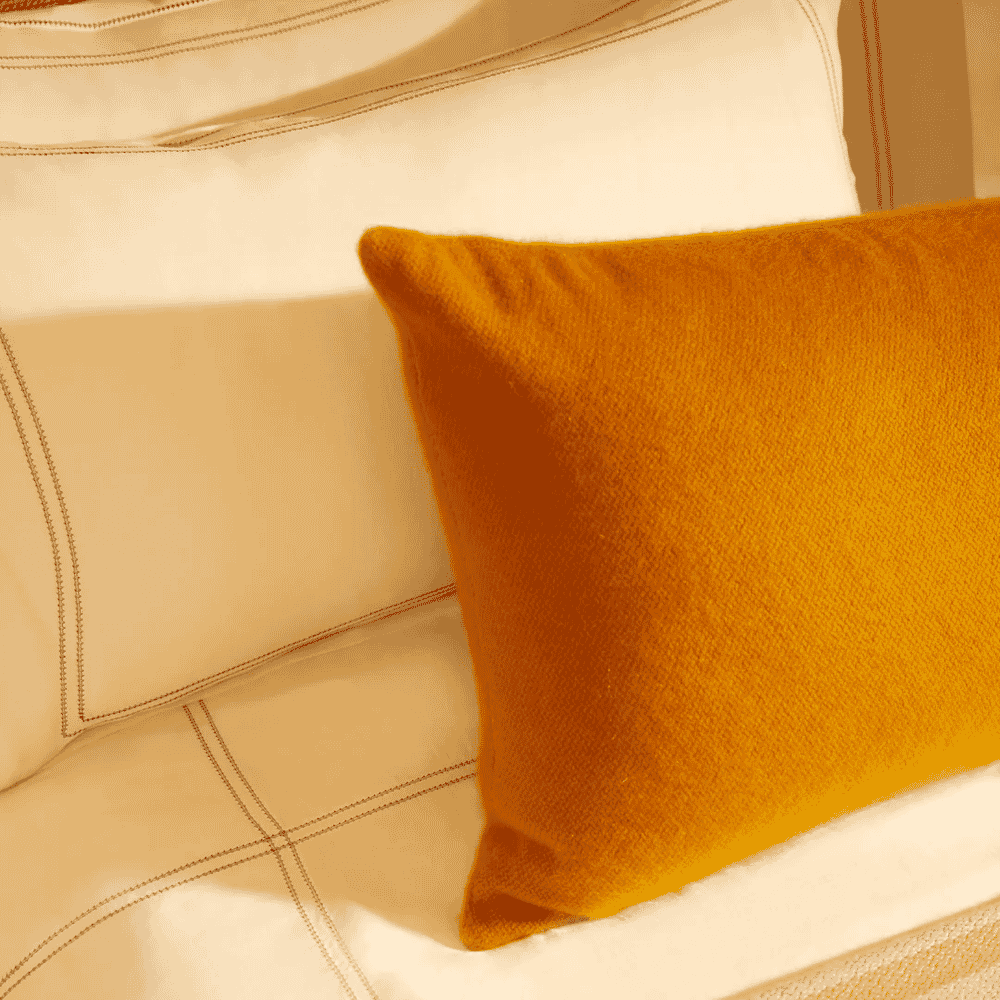 A vibrant mustard-yellow textured pillow on cream bedding.