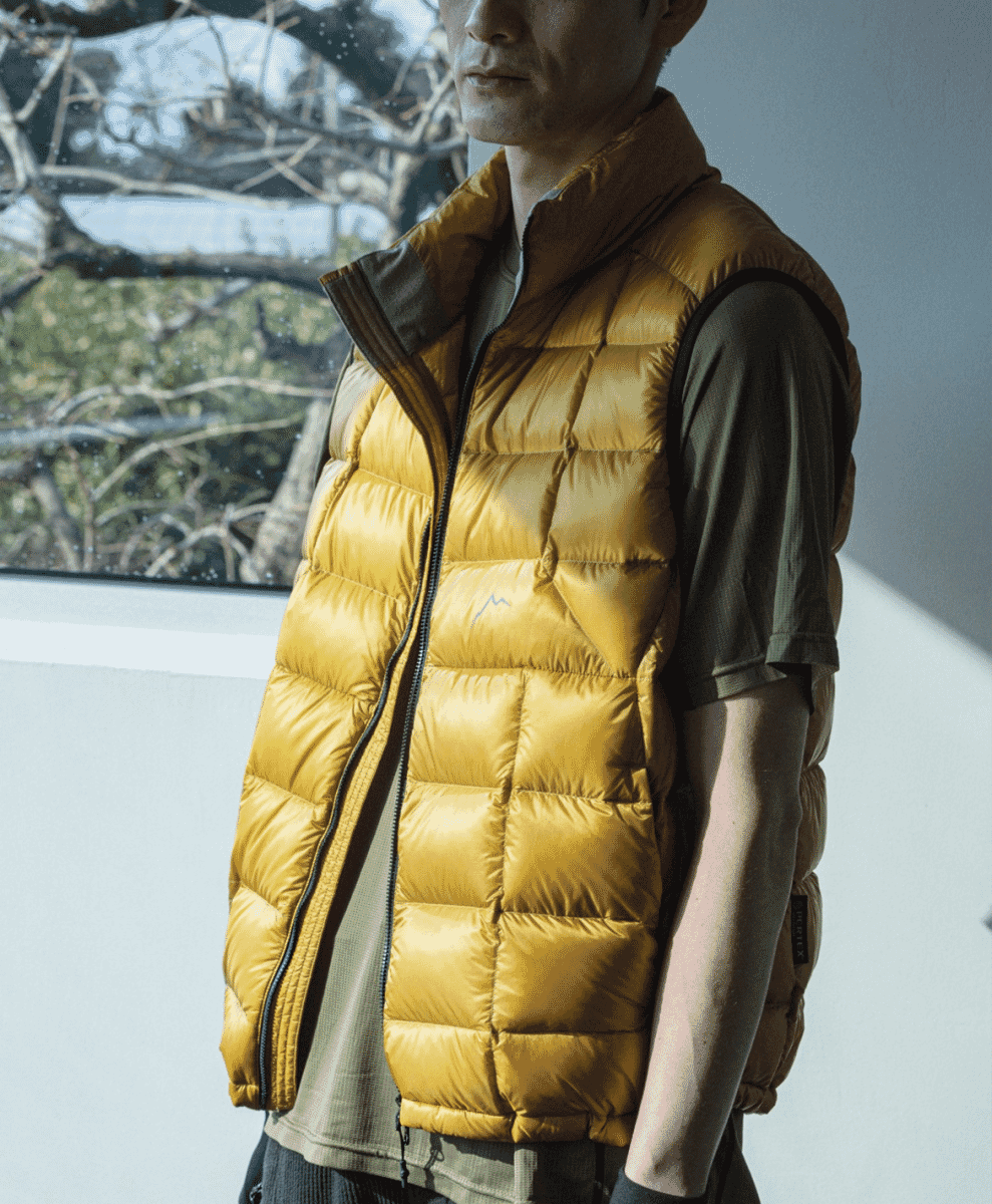 A man modeling a glossy mustard-yellow quilted puffer vest