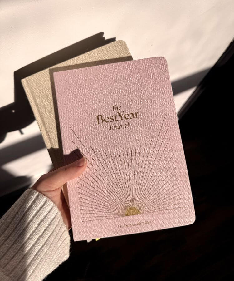 A serene moment of someone writing intentions in a leather-bound journal