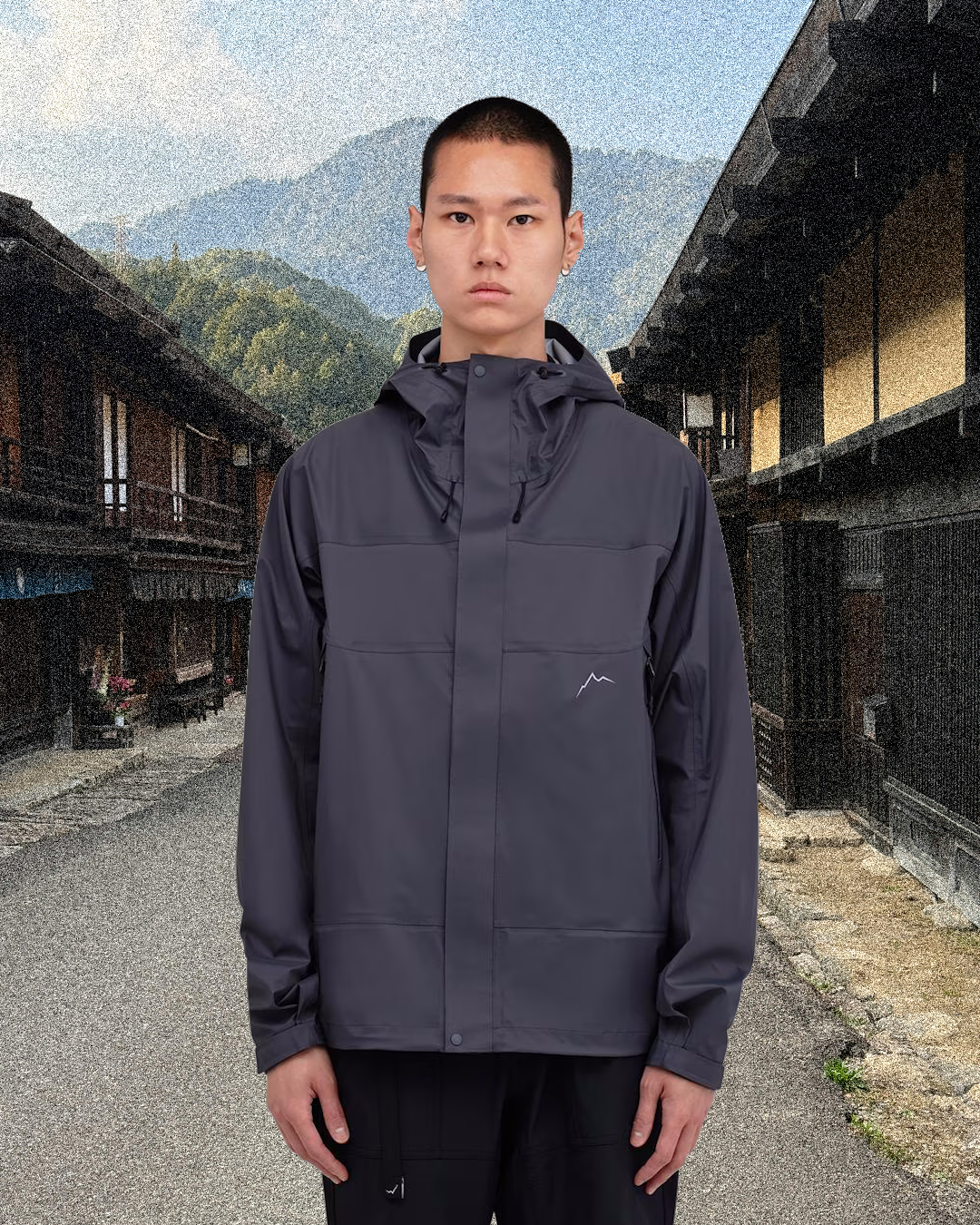 Man in a dark gray hooded outdoor jacket on a traditional Japanese village street.