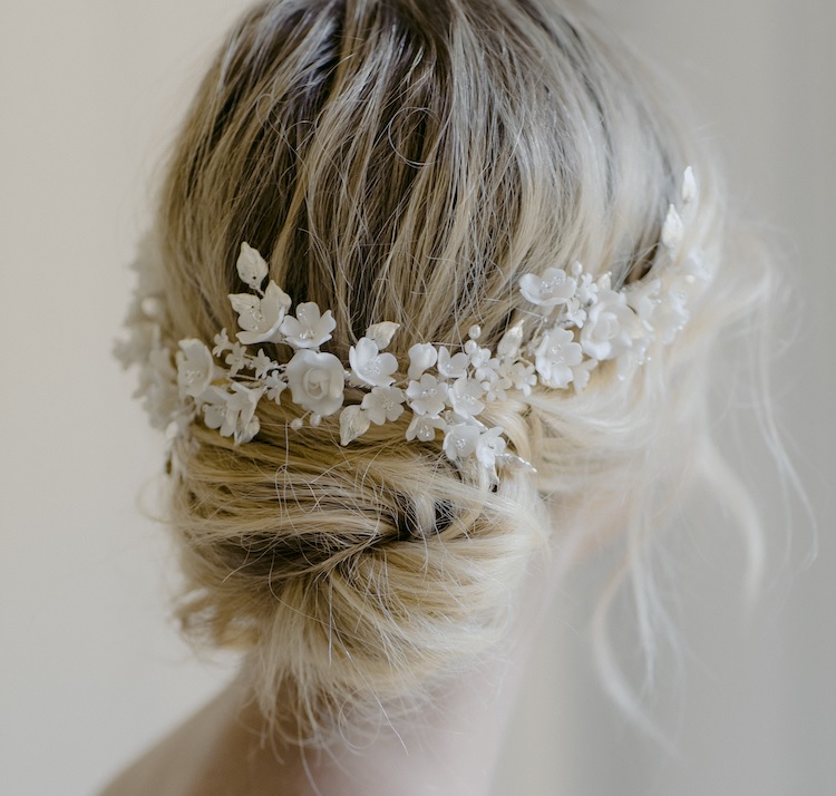 Close-up of a blonde bride wearing an intricate white floral headpiece in a soft updo.