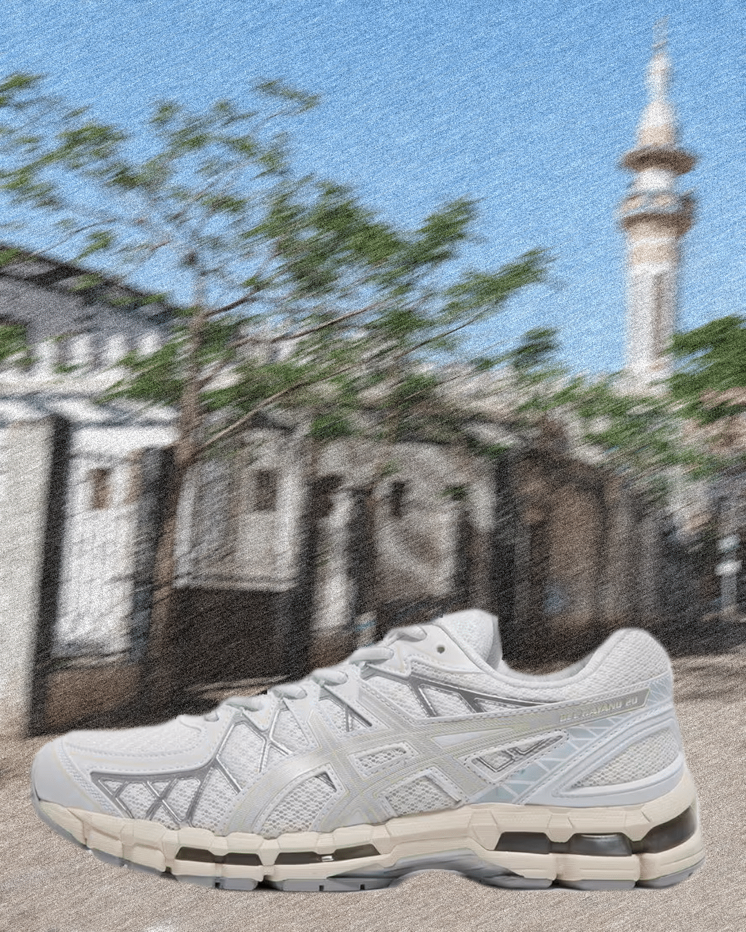 White Asics sneaker with silver metallic details positioned in front of historic architecture.