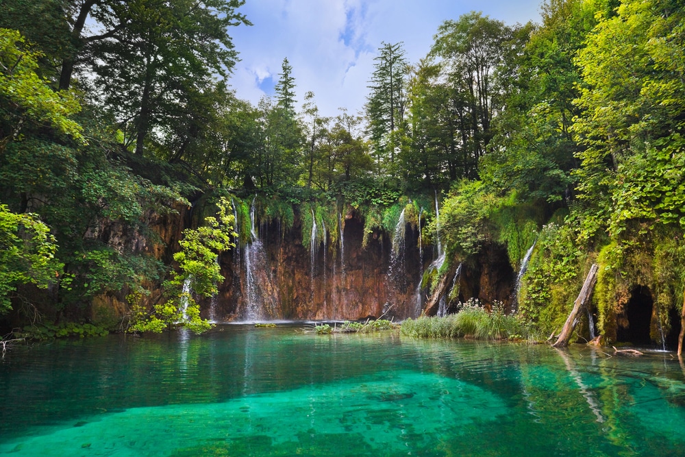 Cascading waterfalls and crystal-clear turquoise lakes surrounded by lush greenery.