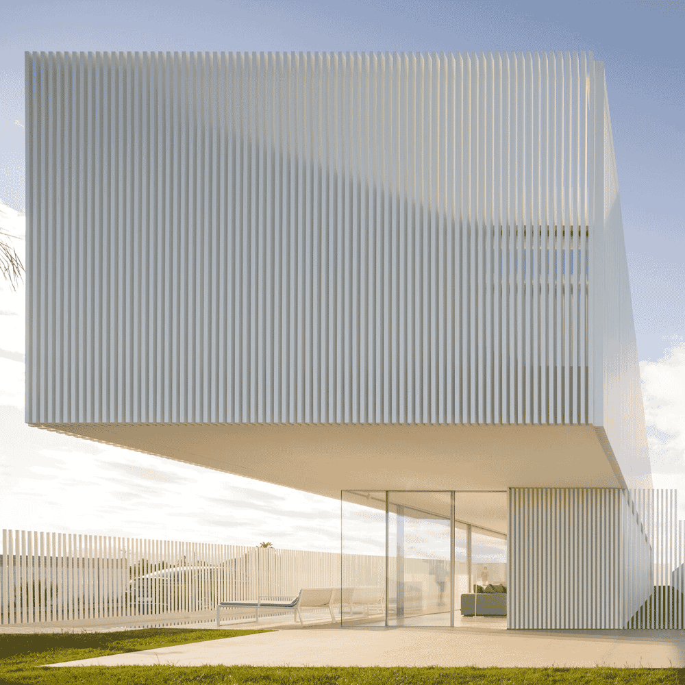 Close-up of a cantilevered roof and outdoor seating area integrated into a minimalist white building.