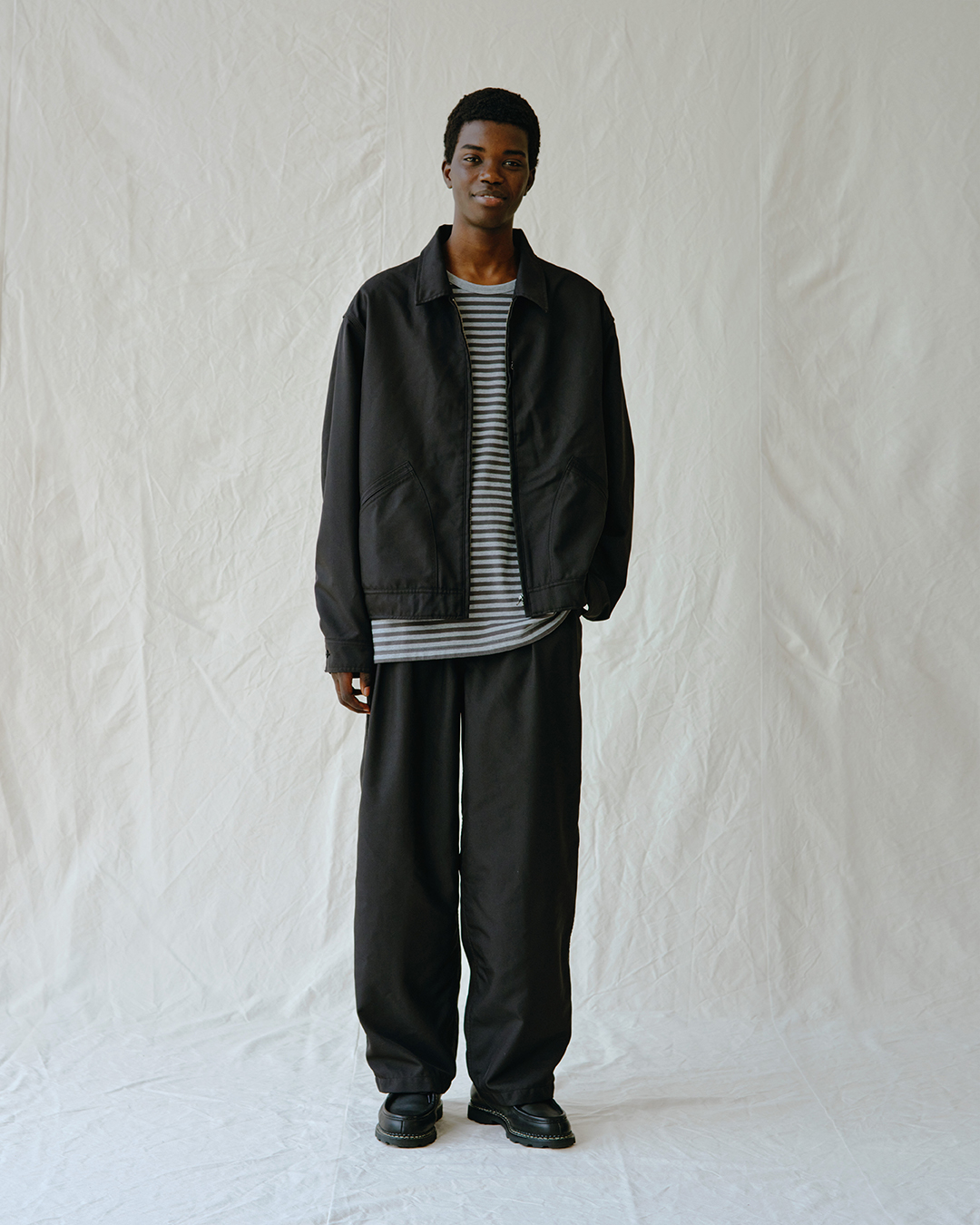 Model wearing an oversized black jacket and wide-leg black pants.