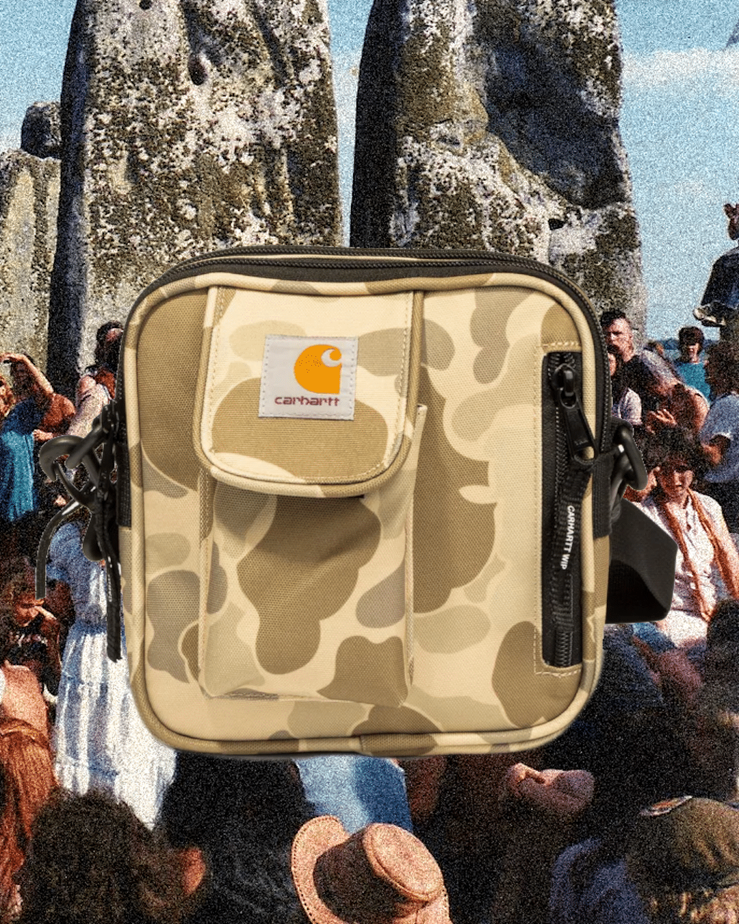 Carhartt camouflage crossbody bag with an orange logo placed over a vintage festival crowd scene.