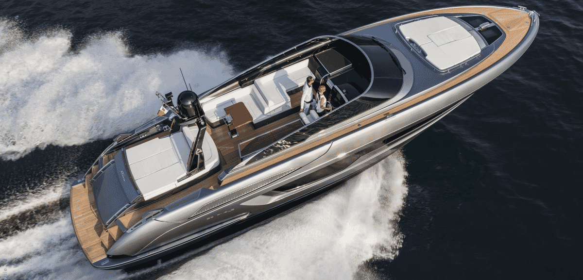 Two people in upscale leisurewear cruising on a luxury speedboat with white wake
