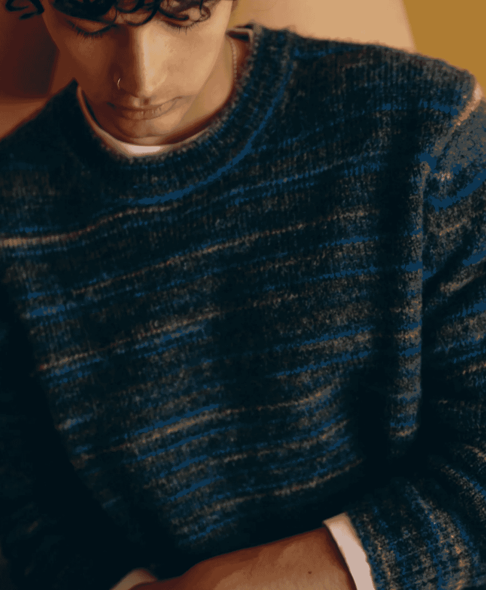 A man wearing a textured, space-dyed crewneck sweater in blue and teal.