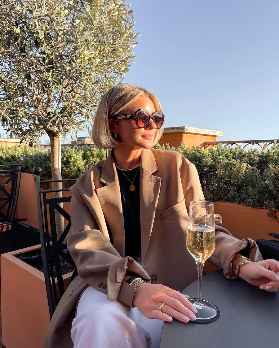 A person peacefully reading a book while reclining on a blanket in a lush green park.