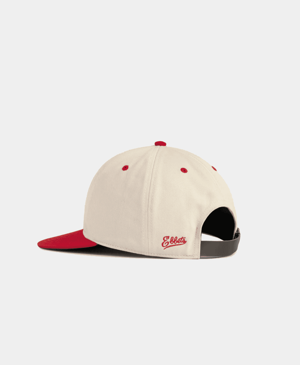 Side view of cream cap with red 'Ebbets' script embroidery.