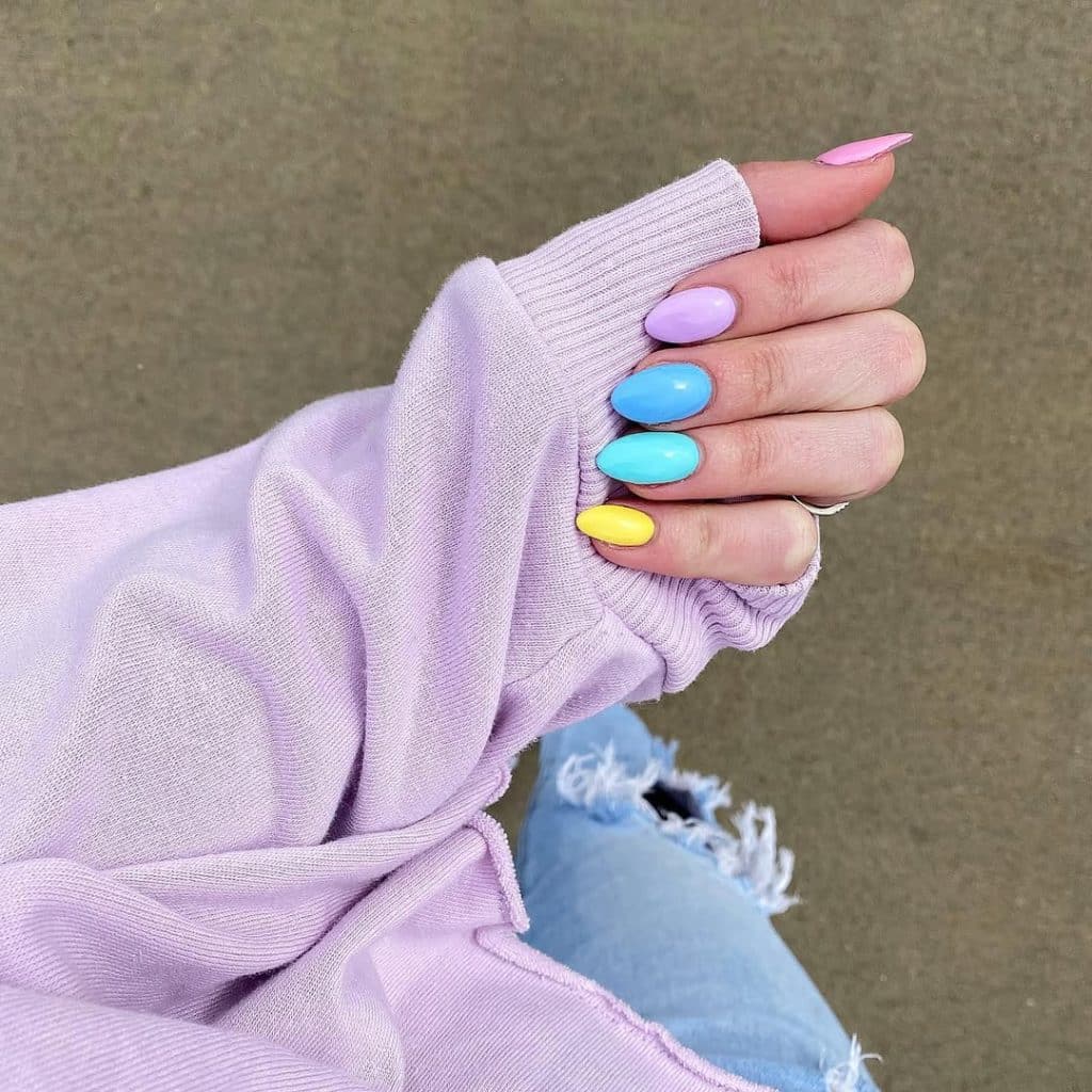 Colorful pastel nail art against a soft lavender ribbed sweater and jeans.