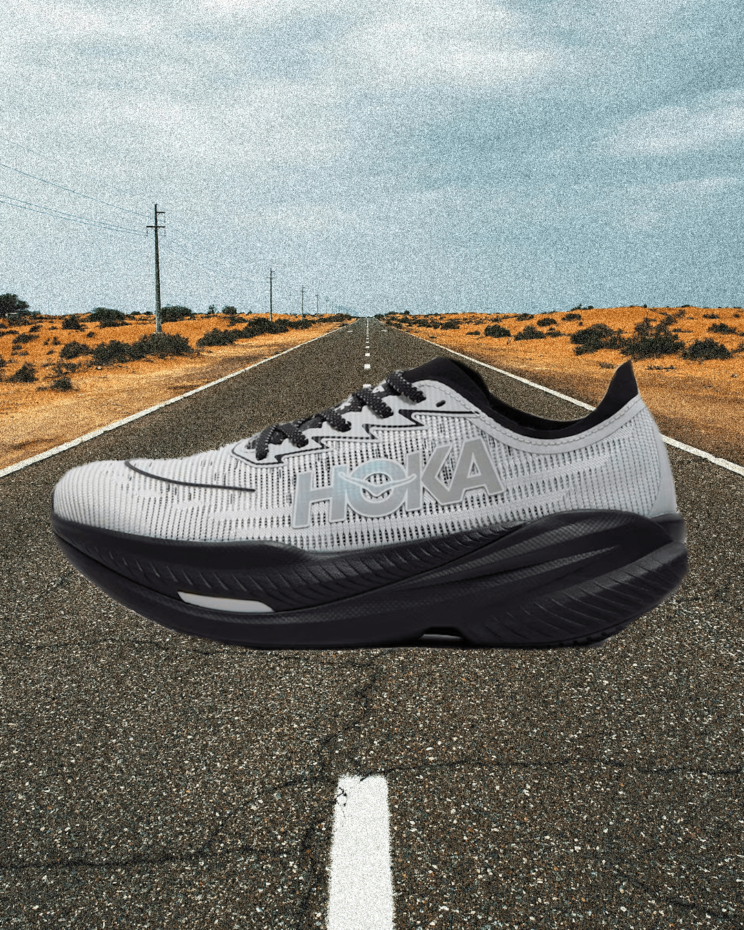 A white Hoka running shoe prominently displayed on an open desert highway.