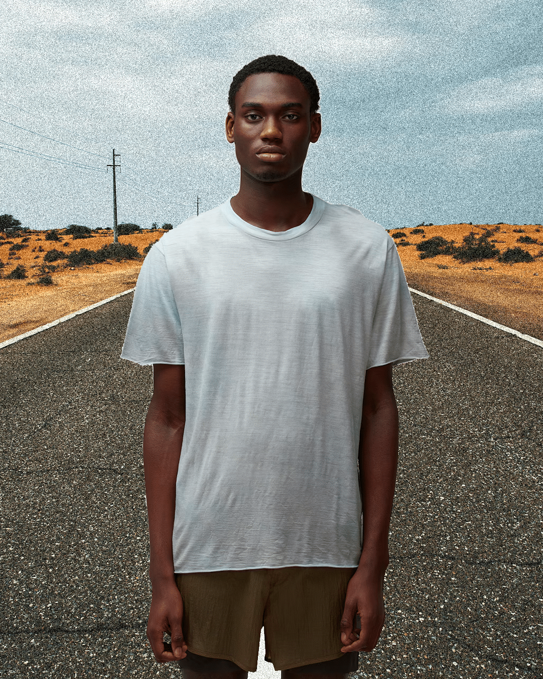 A man in a minimalist gray t-shirt and olive shorts against an arid desert background.