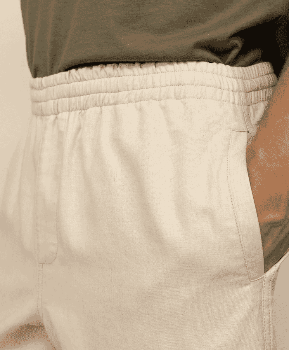 Close-up of the elastic waistband and pocket detail on white linen shorts