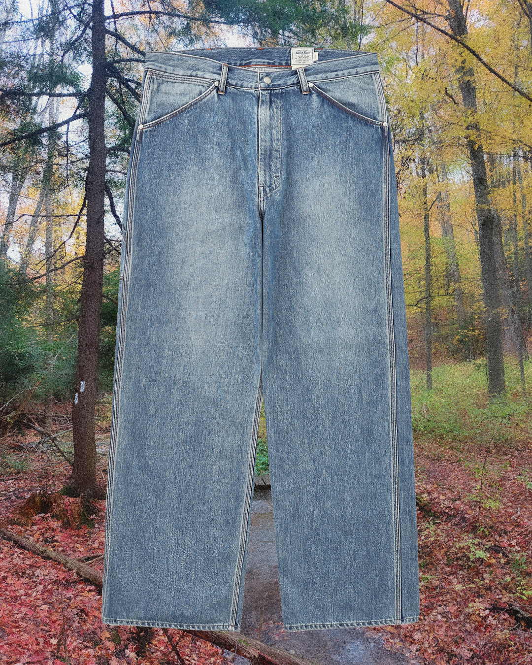 Light-wash wide-leg denim jeans with visible stitching in a forest setting.