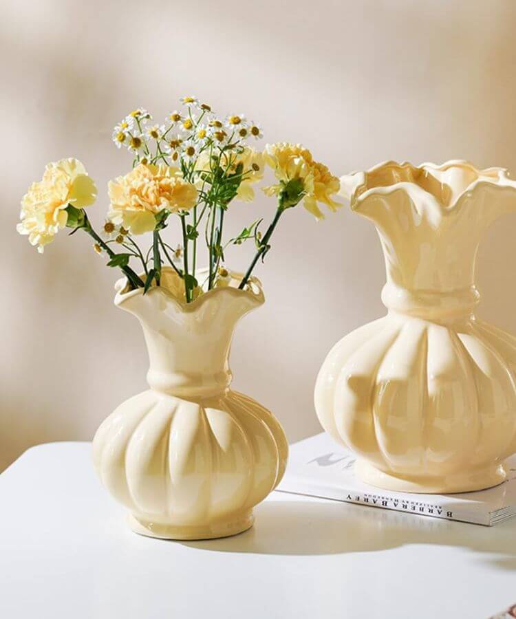 Minimalist butter yellow ceramic vase on a shelf.
