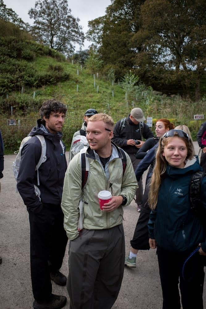 A group of people wearing technical outdoor jackets and backpacks on an overcast trail.