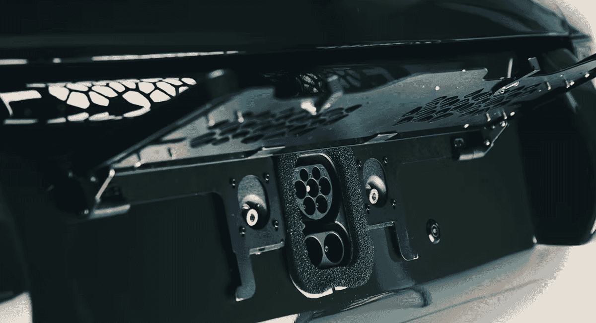 Close-up of a sleek, modern electric vehicle charging port integrated into a black metallic body.