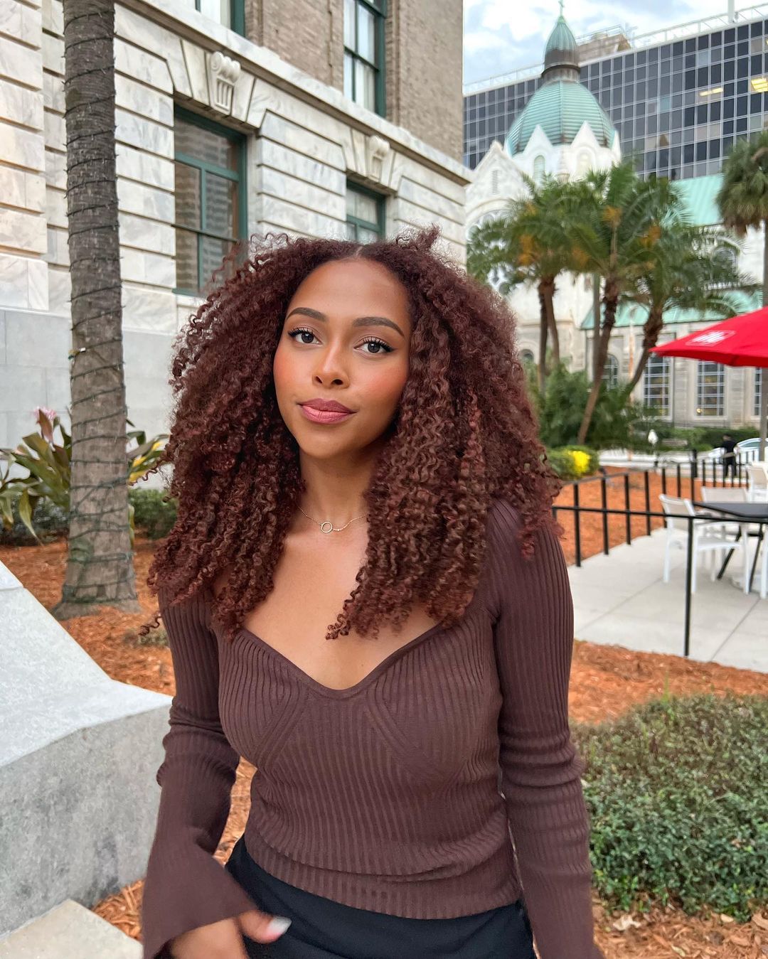 Voluminous curls featuring a blend of chocolate brown and golden copper highlights.