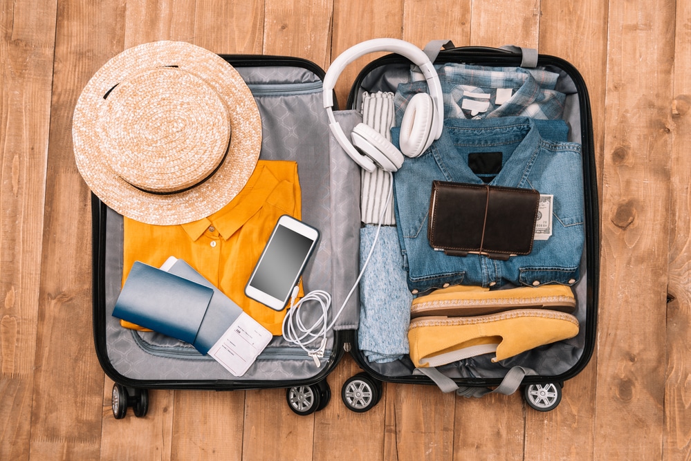 Detail shot of white headphones and travel gear neatly packed in the corner of a suitcase.