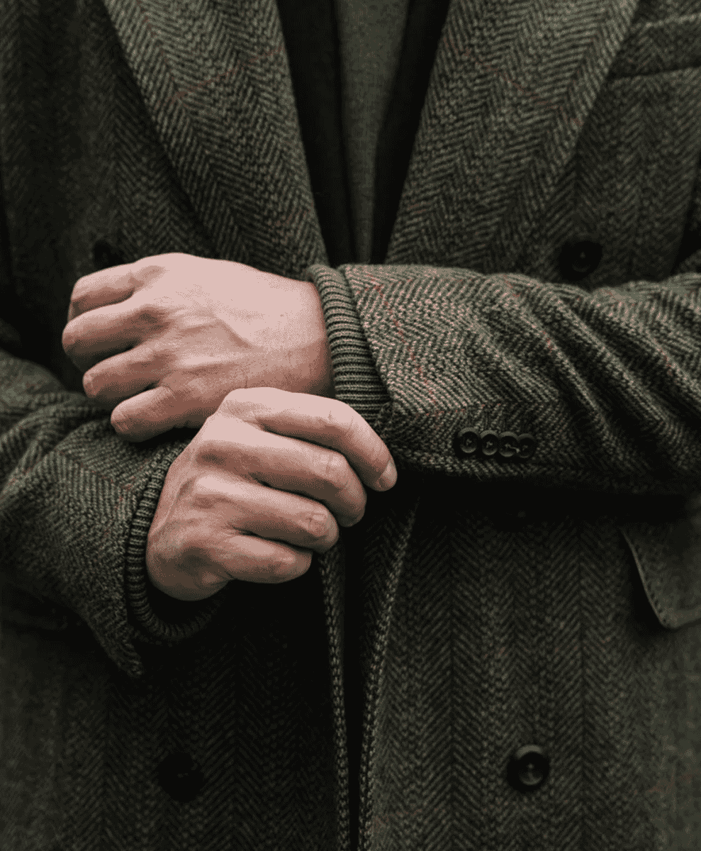 Close-up of a dark green herringbone tweed double-breasted coat.