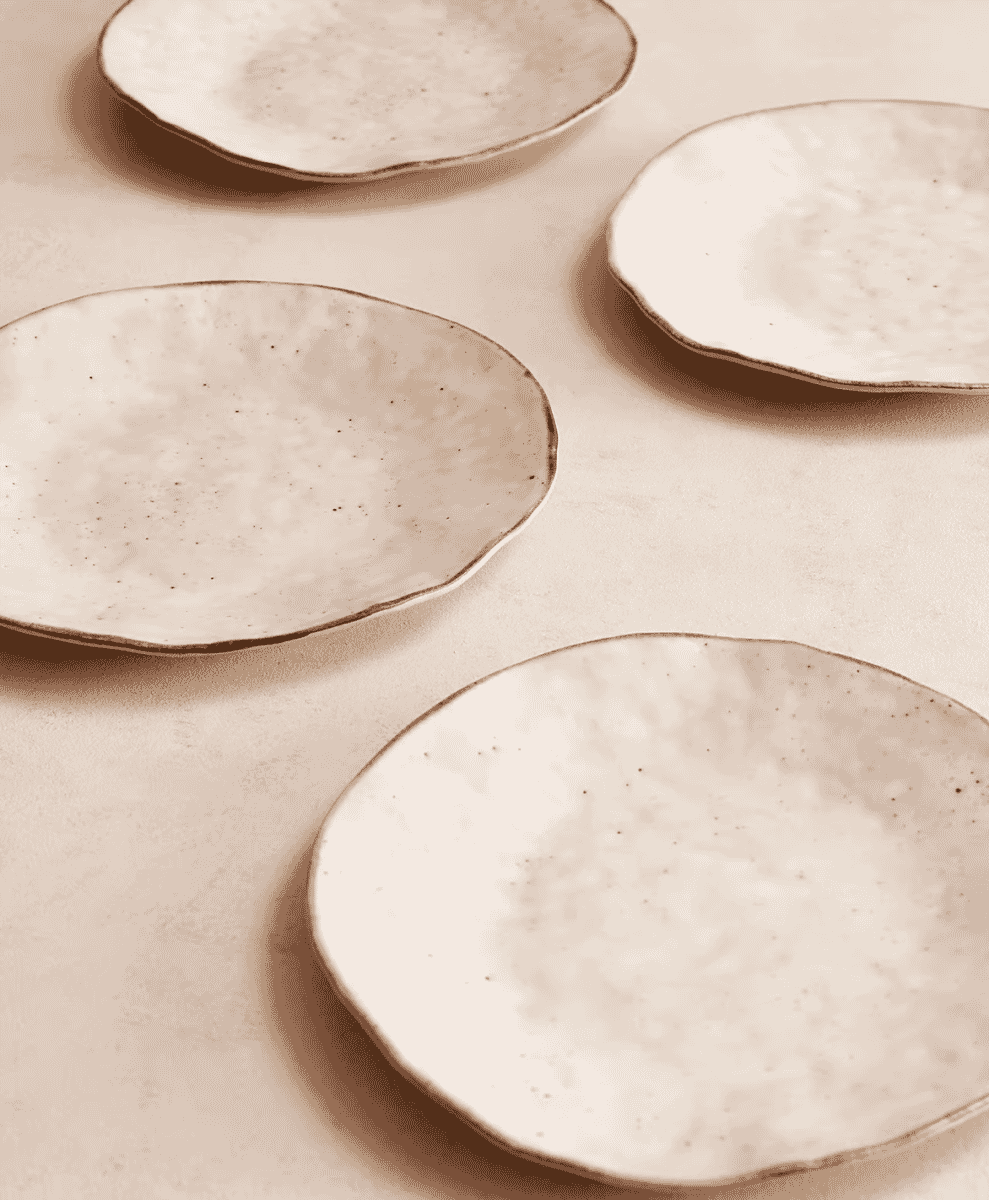 Handmade speckled ceramic plates with irregular edges in warm tones.