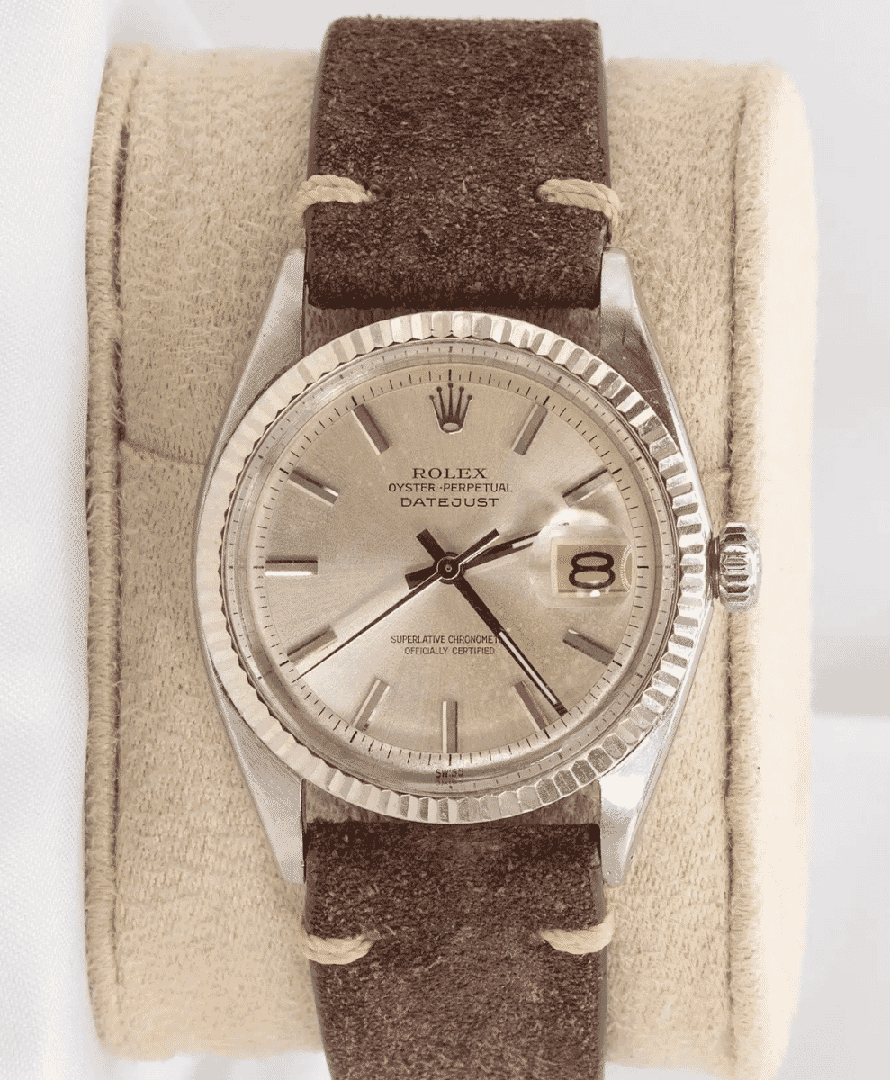 A vintage Rolex Datejust 1601 with a silver dial and a brown suede strap.
