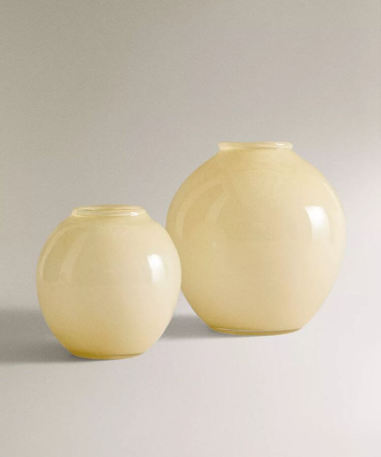 Round, globular glass vase in a soft yellow hue.