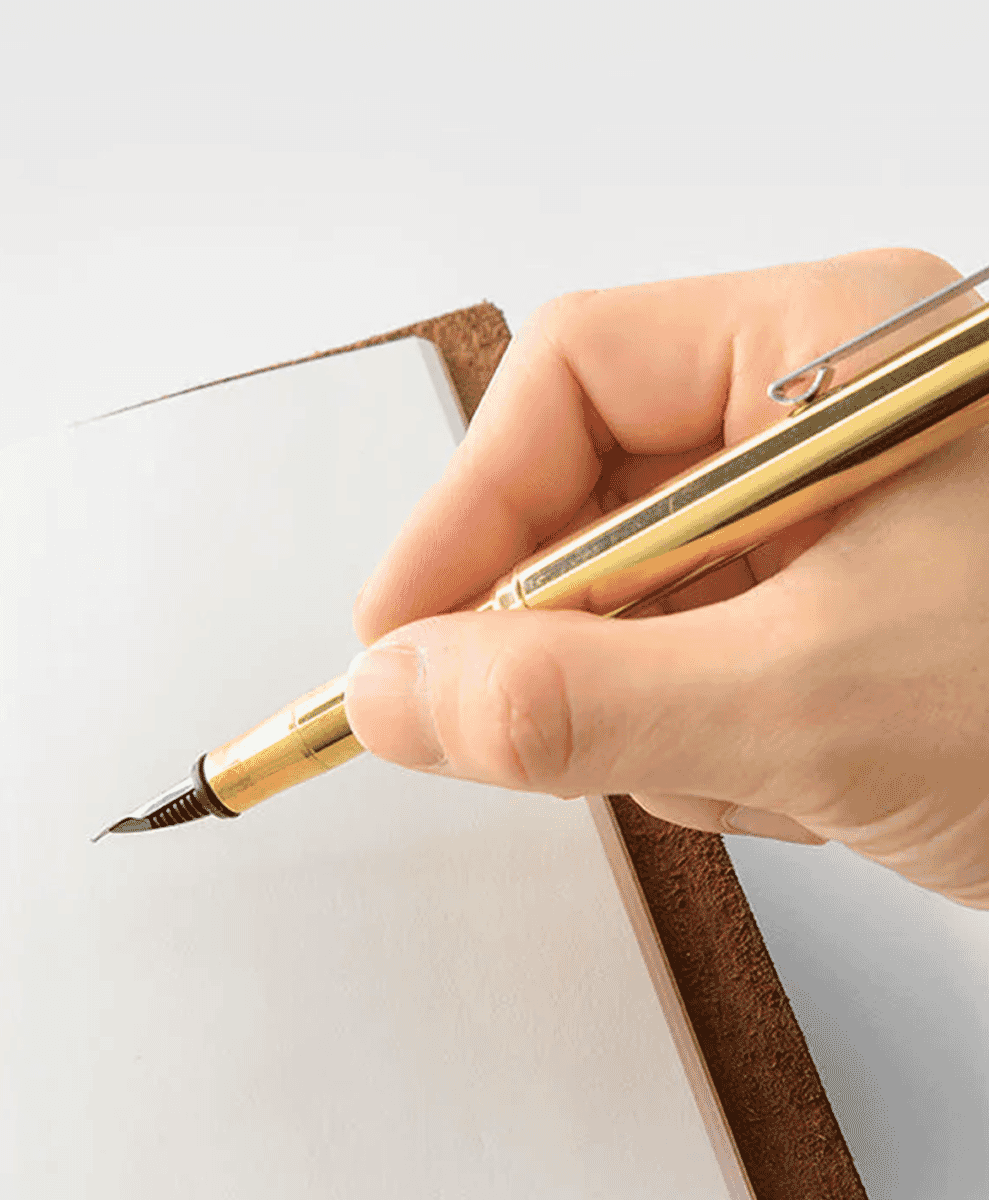 Close-up of a hand holding a gold luxury fountain pen.