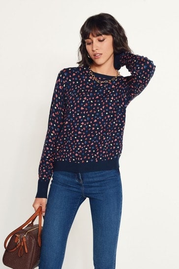 Woman wearing a navy blue floral print sweater and blue jeans.