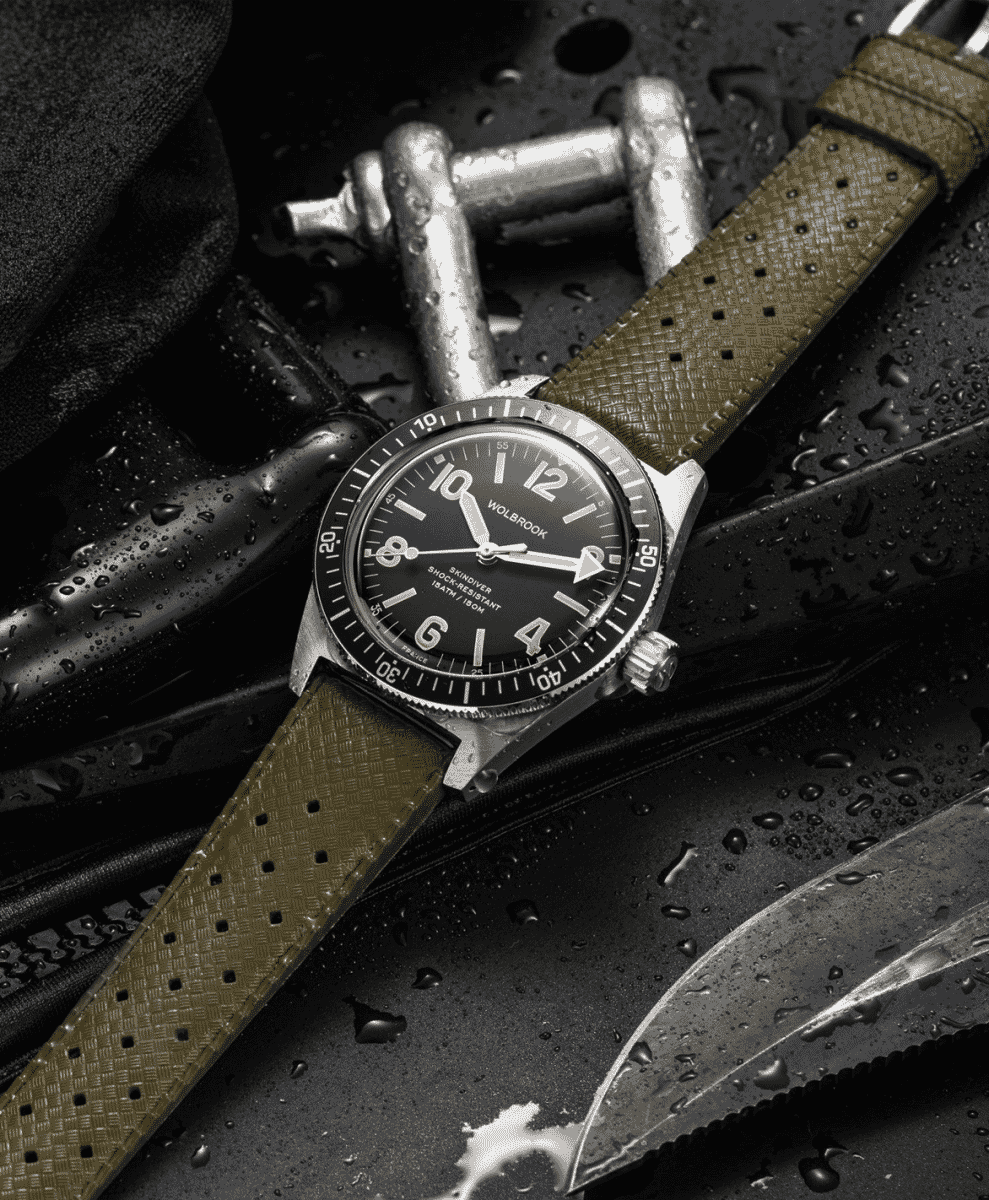 A dive watch with a black dial and olive green perforated strap.