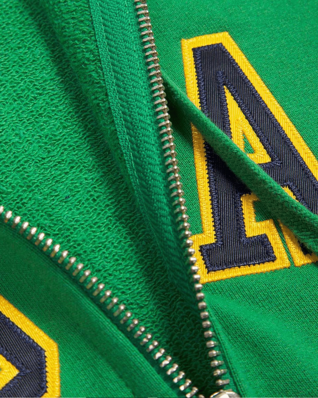 Close-up of a green fleece jacket with an embroidered navy and yellow letter A.