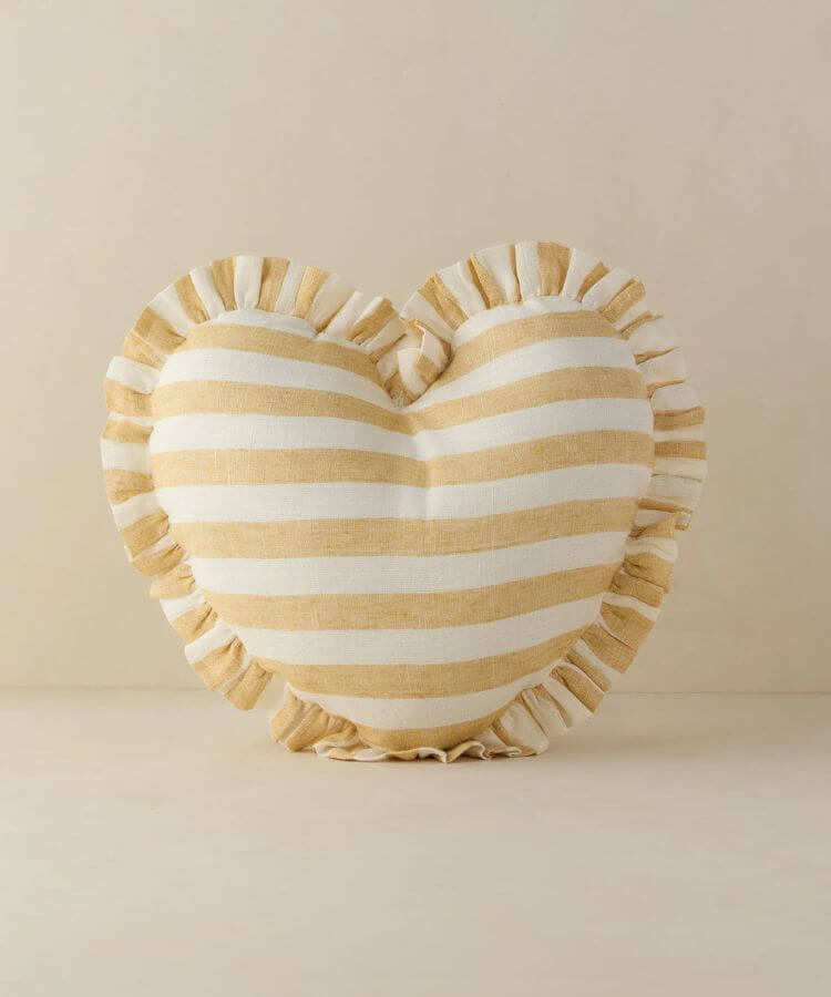 Heart-shaped linen pillow with ruffle edges in soft yellow.
