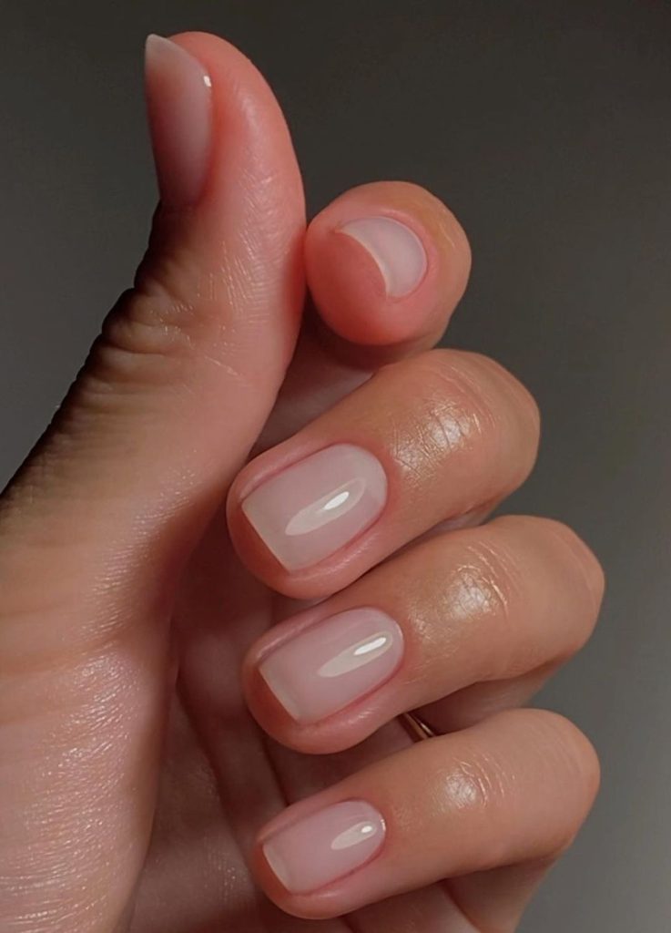 Close-up of manicured hands with sheer white, soap-textured nail polish.