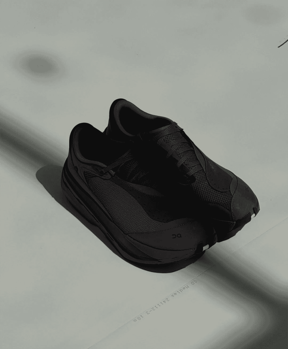 Top-down view of all-black athletic sneakers on a light gray surface.