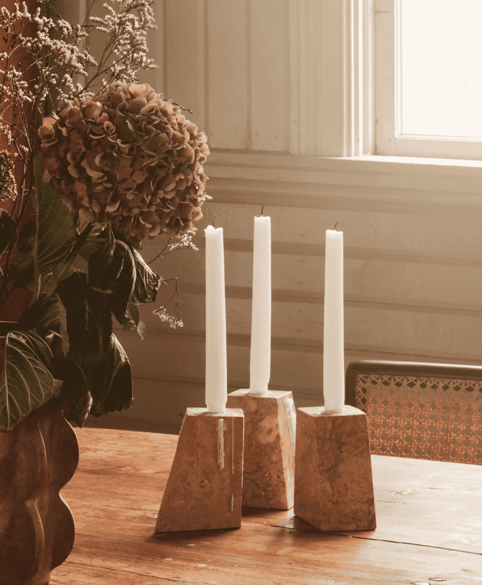 Marble candle holders and dried flowers on a rustic wooden table.
