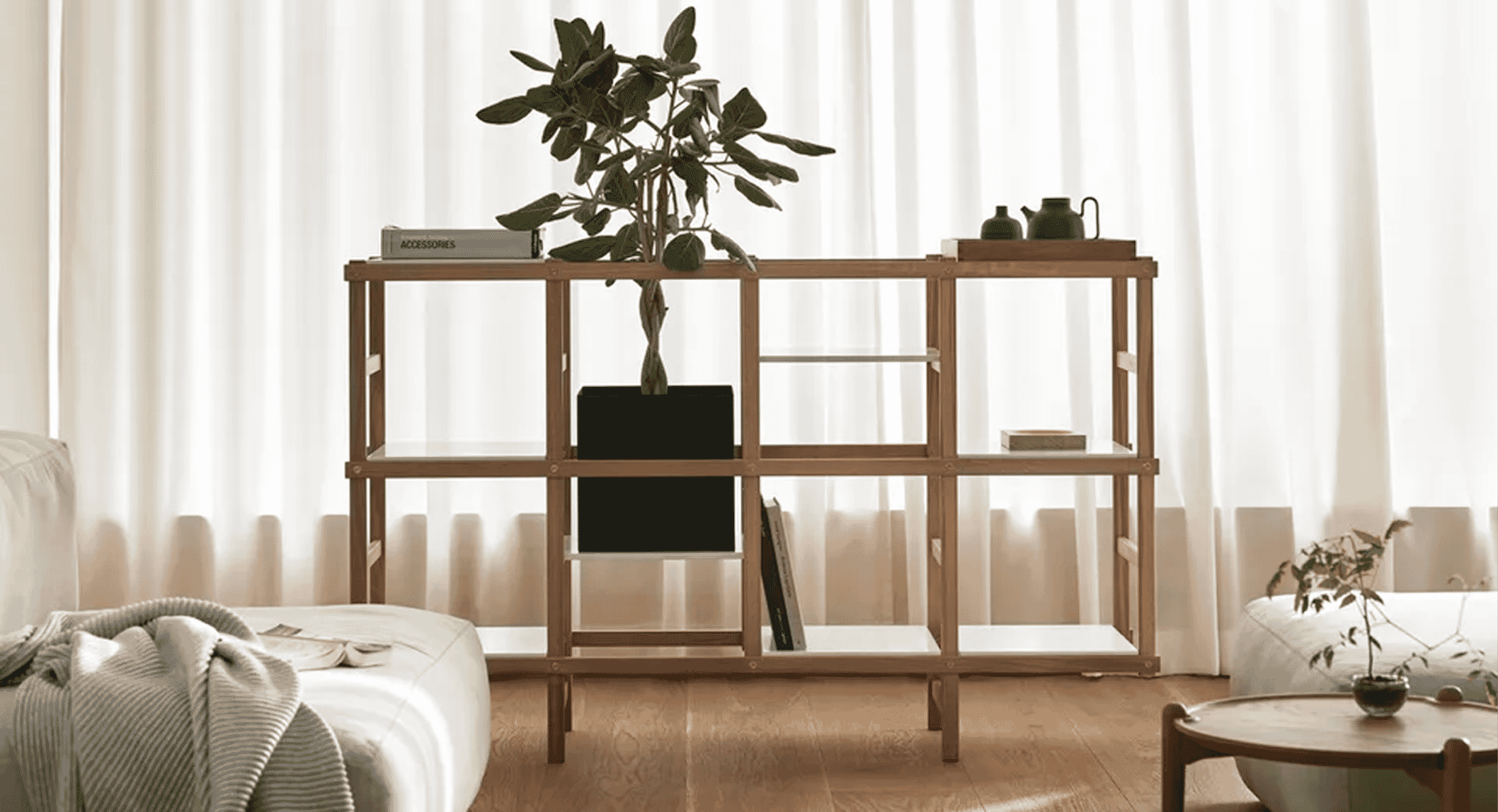 Modern living room with light oak shelving, a potted plant, and neutral-toned furniture.