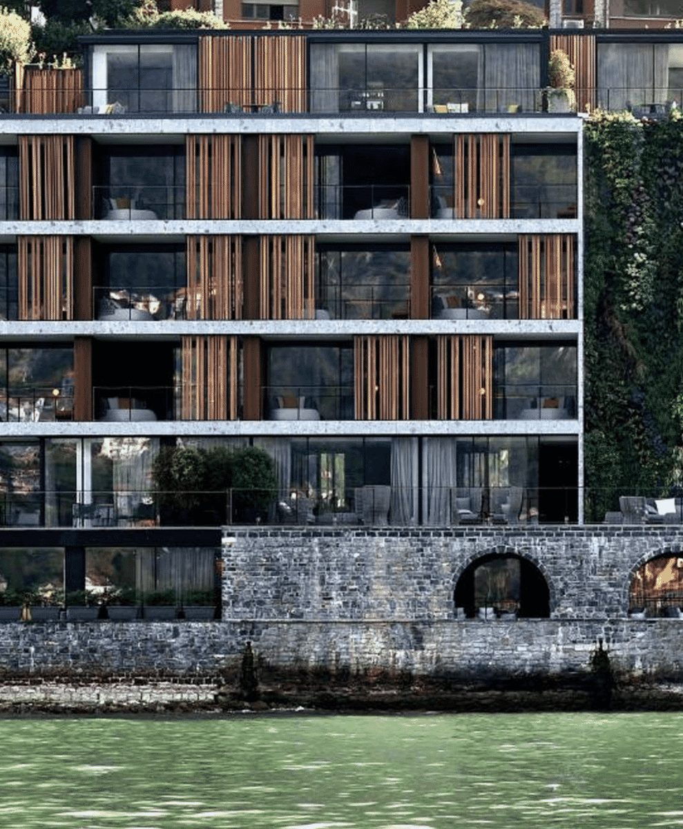 Modernist architecture of Il Sereno hotel featuring vertical gardens, stone walls, and wooden slat facades on the waterfront.