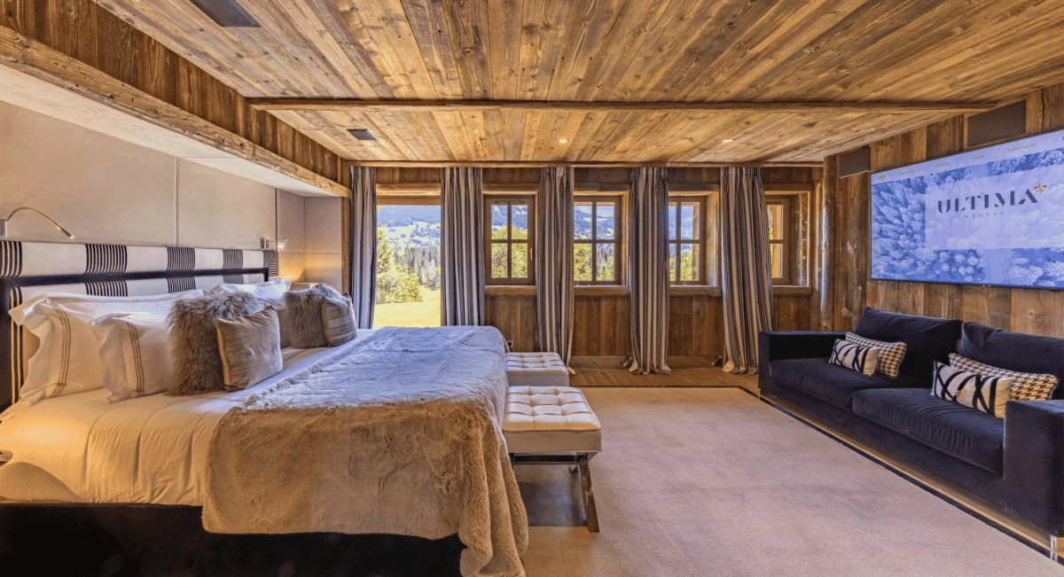 Modern rustic mountain lodge bedroom with wooden ceilings and scenic window views.