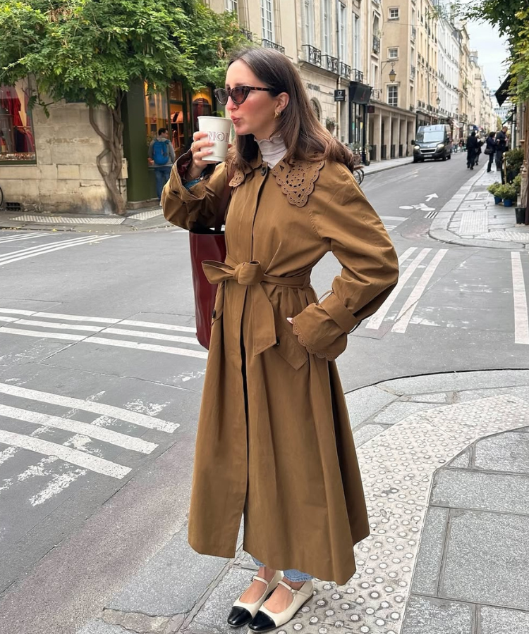 Street style shot of @mariellehaon wearing a trench coat, white socks, and black Mary Janes.