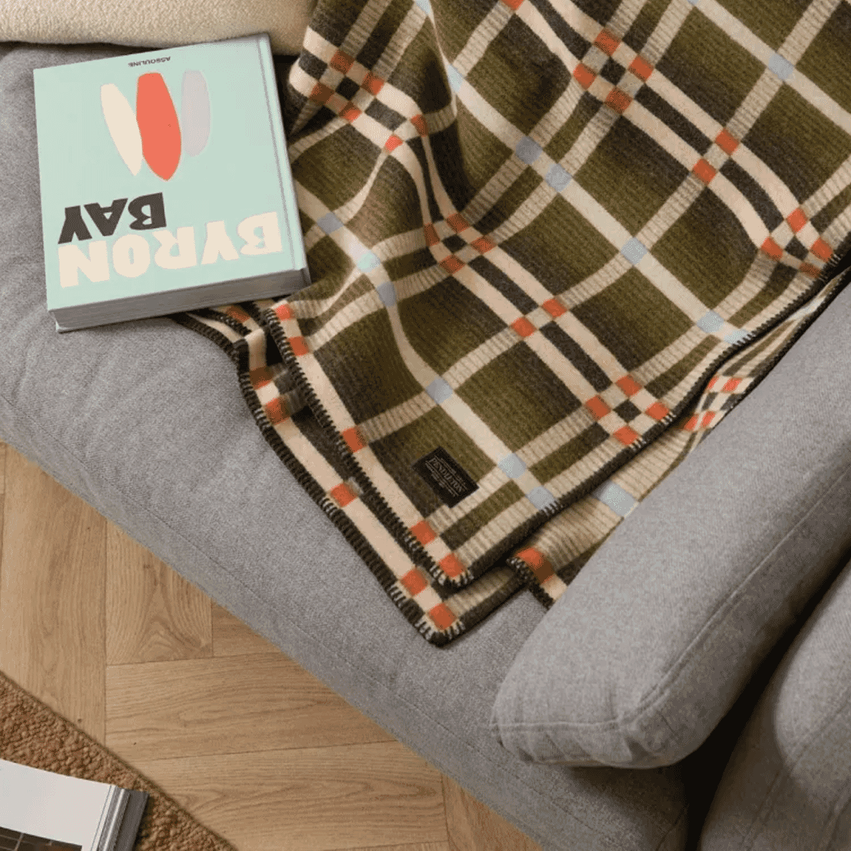 A colorful Pendleton Four Square plaid throw blanket draped over a gray sofa.