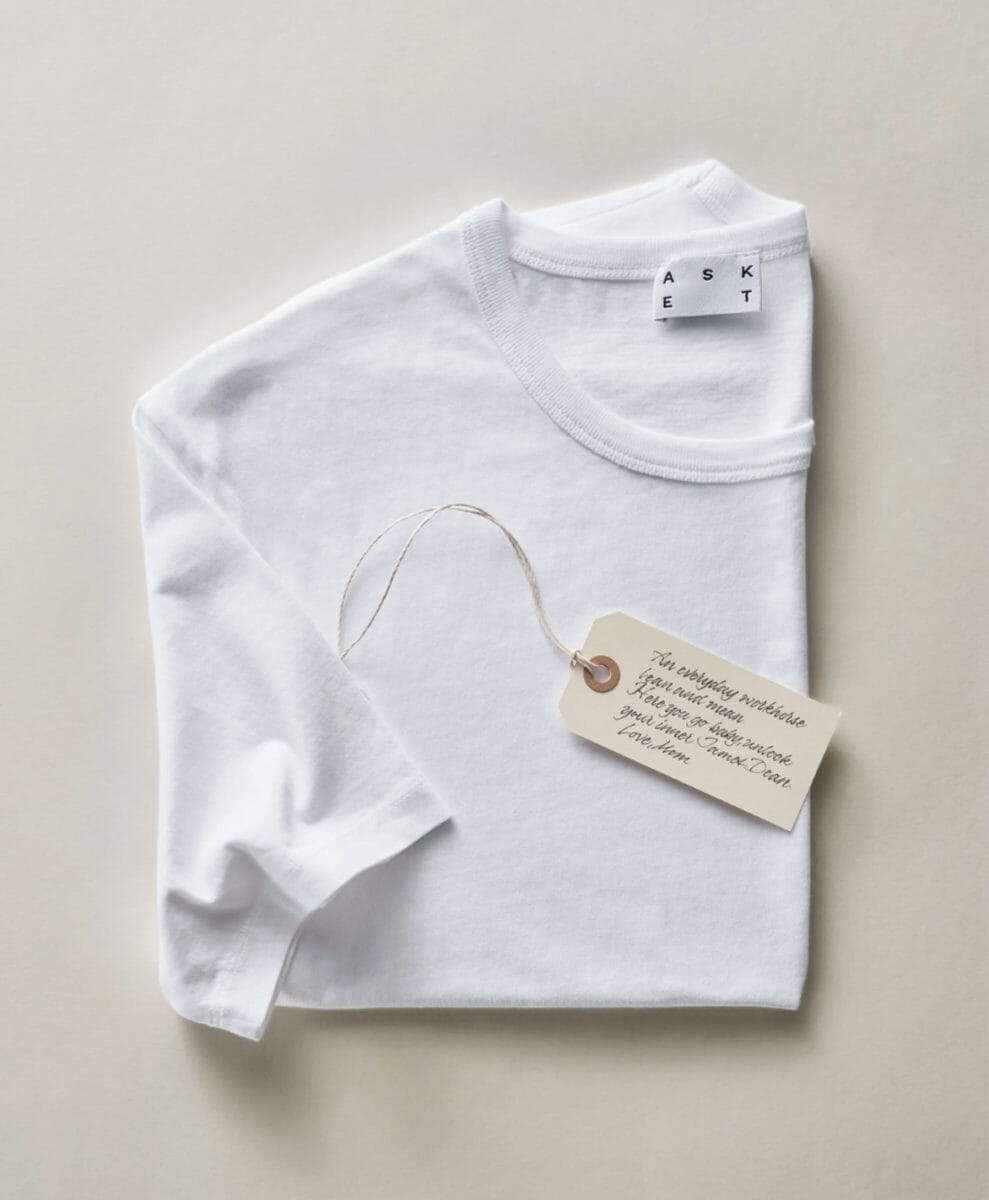 Neatly folded white long-sleeve t-shirt with a branded tag and handwritten note.