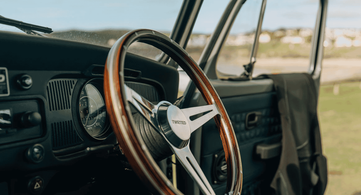 Interior of a vintage car featuring a wood-rimmed steering wheel and leather dashboard.