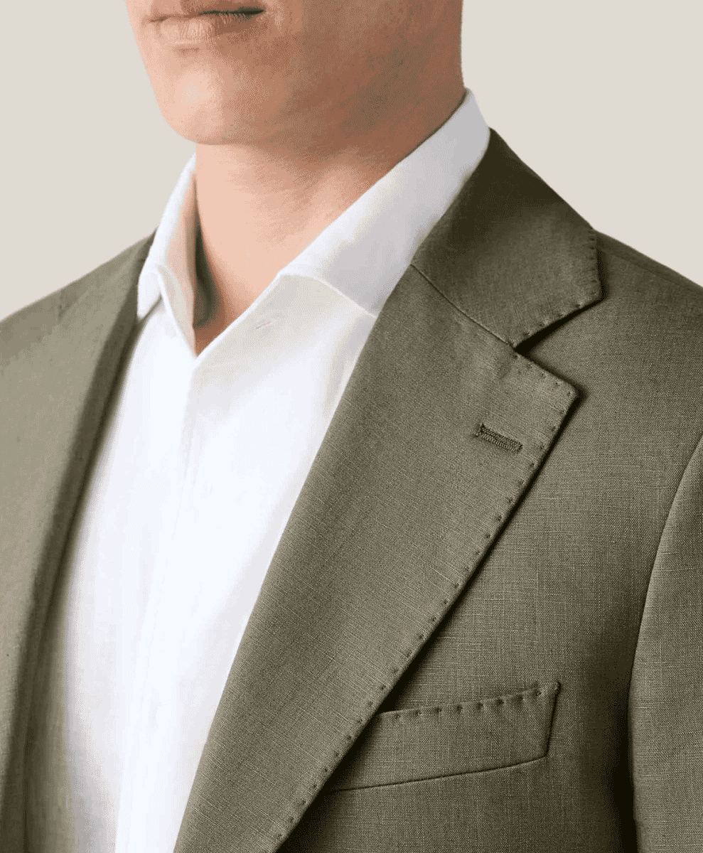 Close-up of a tailored olive-green suit jacket highlighting the fine stitching and lapel.
