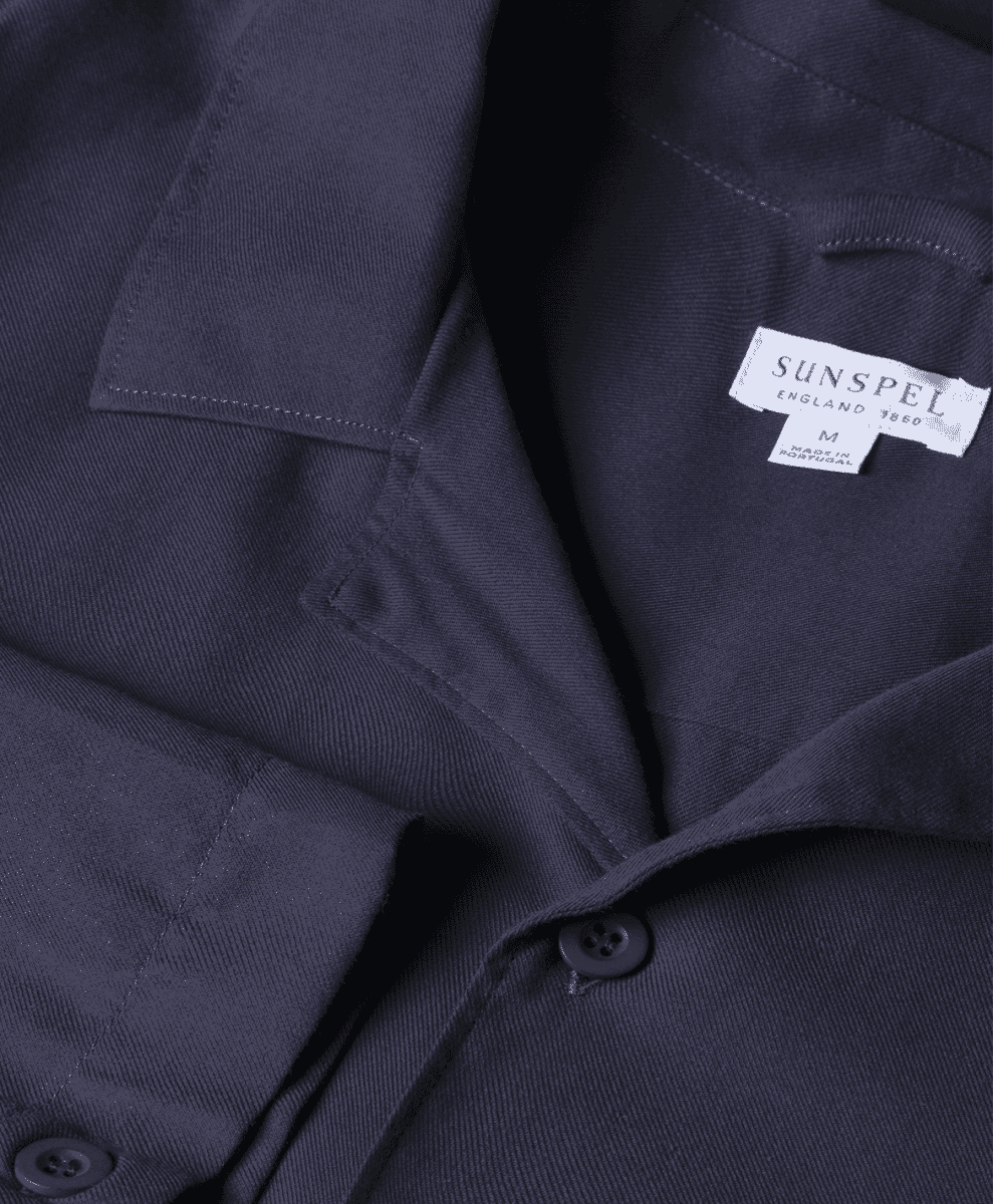 Close-up of a Sunspel England brand label on a navy blue shirt collar.