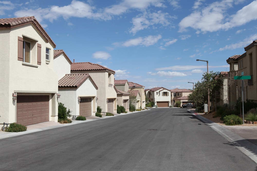 Typical Las Vegas suburban neighborhood with beige stucco homes and tiled roofs under a bright sun.