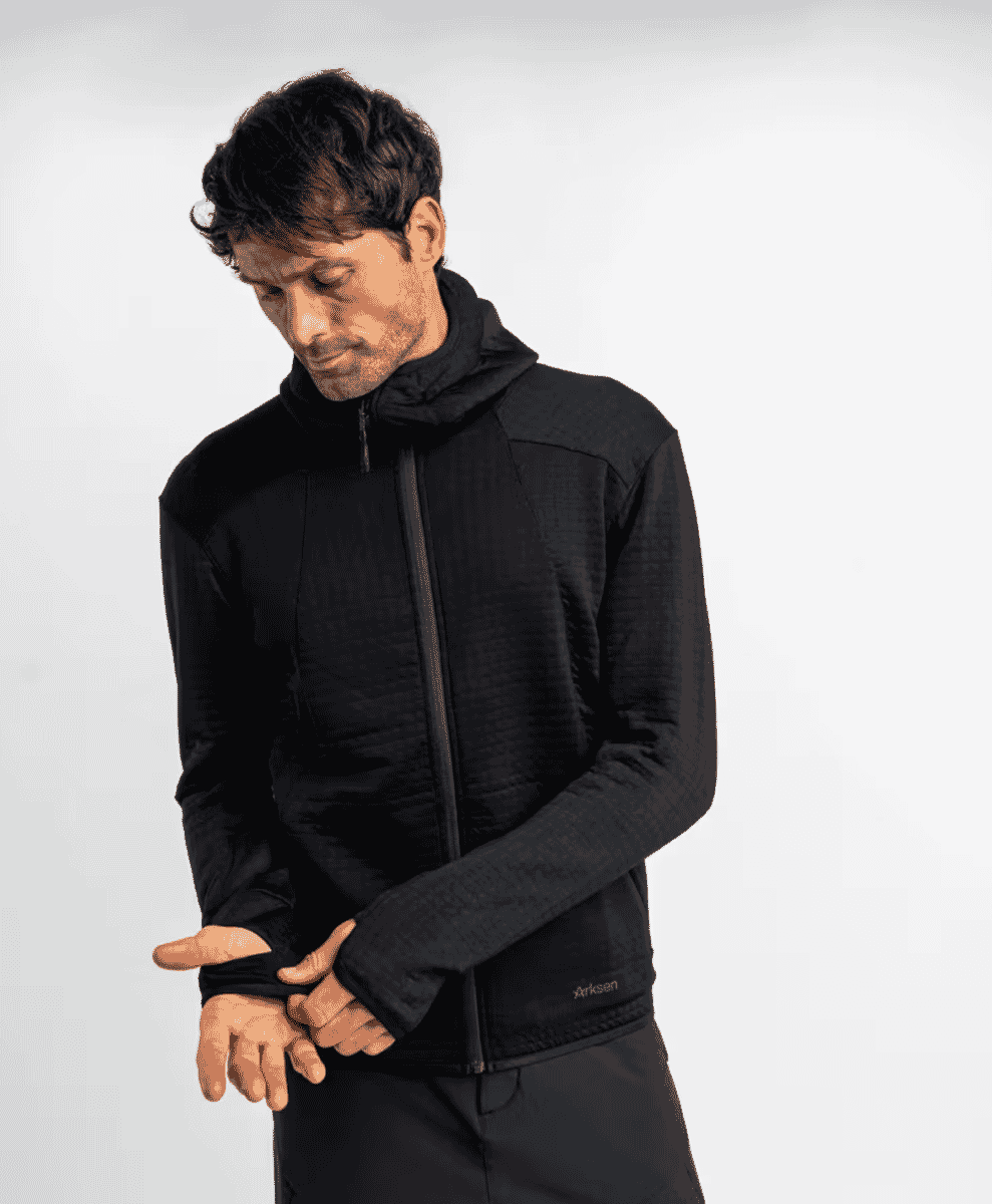 A man modeling a black textured technical hooded jacket with a zip front.
