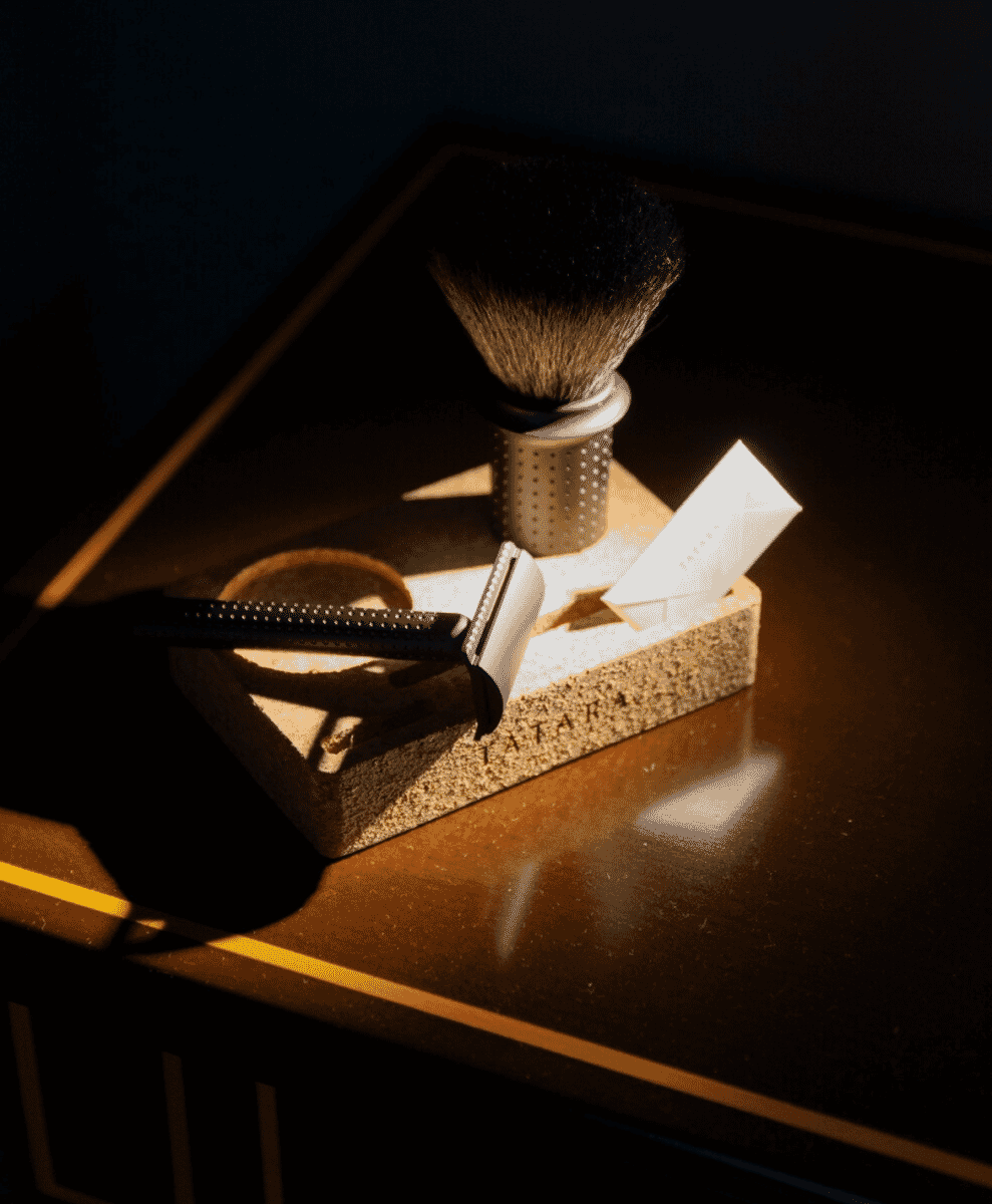 Luxury shaving set featuring a safety razor and brush on a dark stone vanity tray.