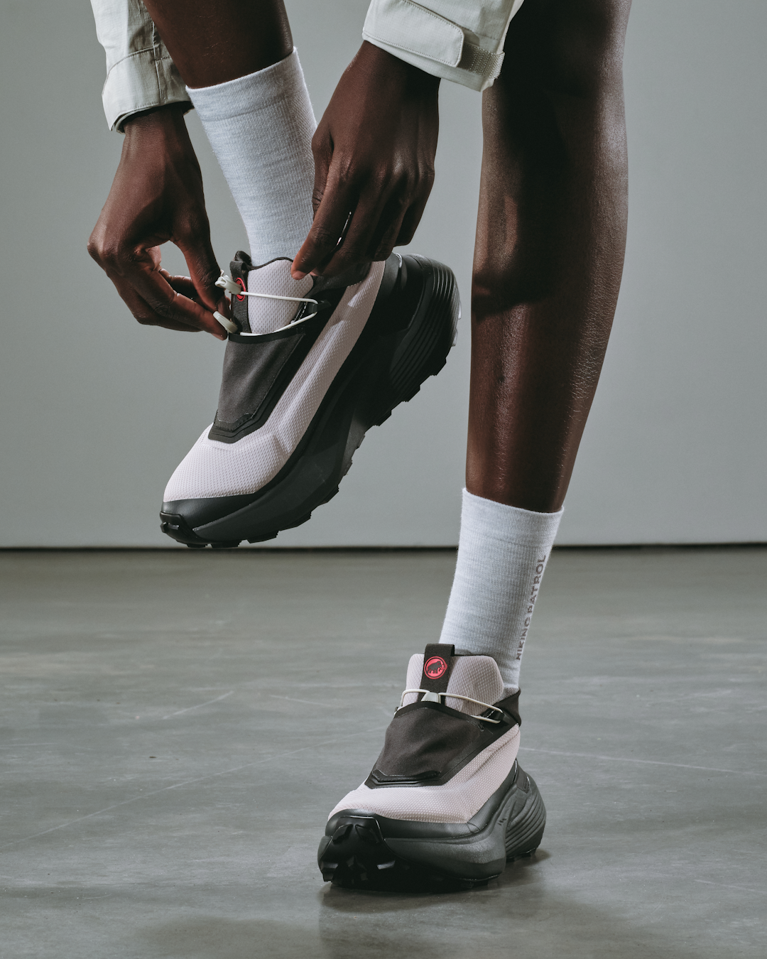 Model walking away into a vast natural landscape wearing full technical gear.